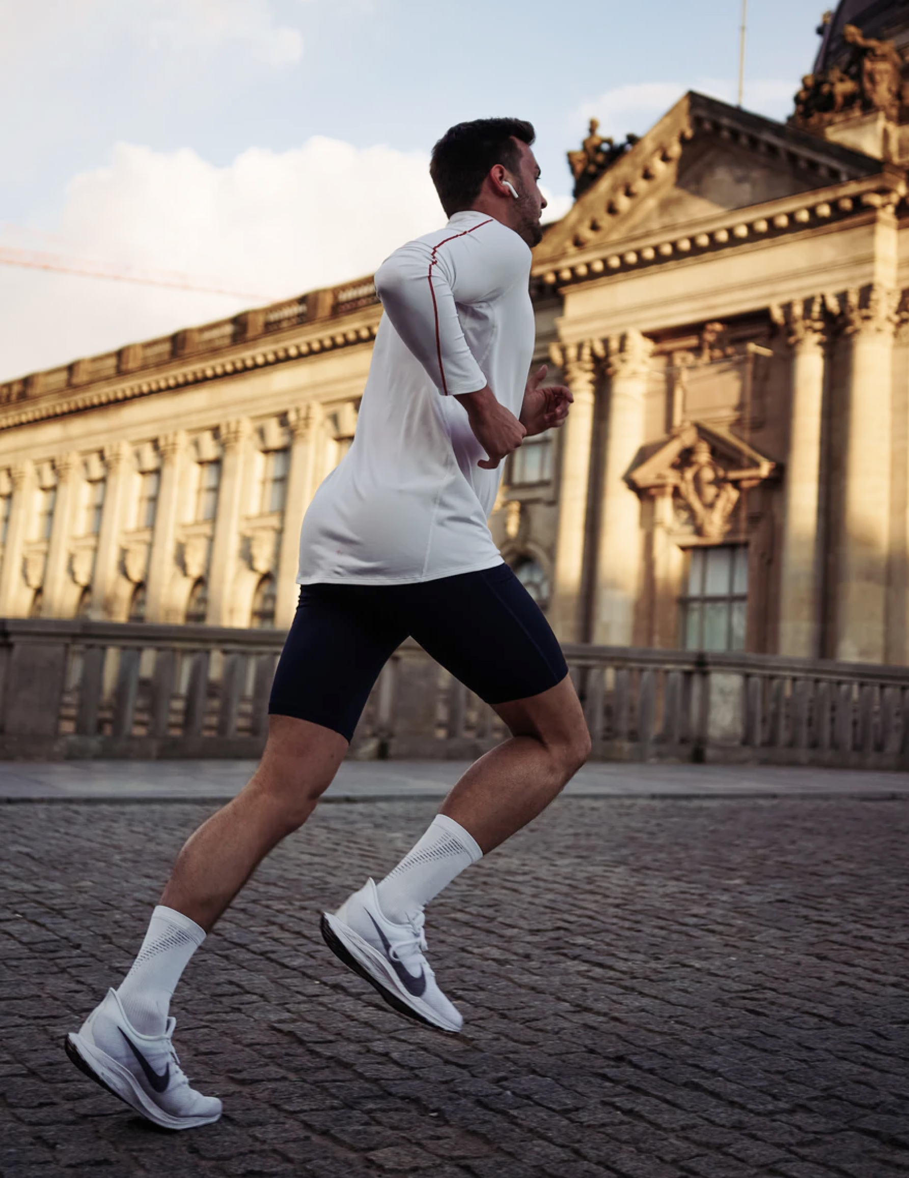 A man running outside with airpods in the ears.